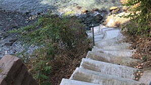 A concrete staircase leading down to a rocky shoreline with clear water. - Beautiful home with private beach just for rest and relaxation. (Manzanillo)