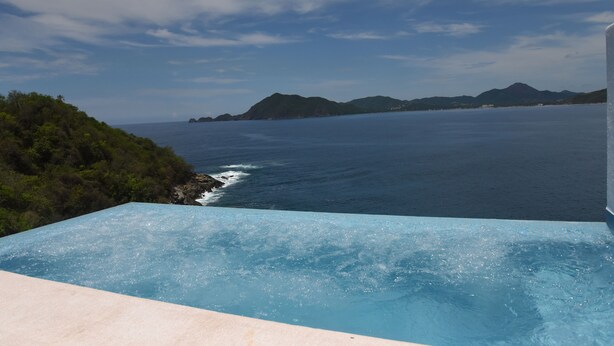 A pool with a view of the ocean and distant mountains. - Beautiful home with private beach just for rest and relaxation. (Manzanillo)