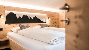 A wooden cabin bedroom with two beds, a wall-mounted light, and a mountain silhouette artwork. - Ski and hiking adventure in the immediate vicinity, away from the crowds, yet close to the center (Selva Gardena - Wolkenstein in Gröden)