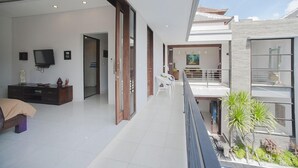 Un interior moderno con un amplio salón, un balcón con plantas y vistas al exterior.