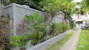 Stroll through the beautifully maintained garden, featuring a variety of plants along a paved walkway.
