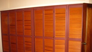 Conjunto de portas de correr em madeira, com uma maçaneta central, provavelmente dando acesso a um armário ou espaço de armazenamento.