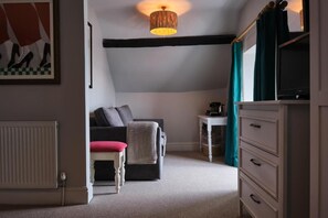 A cozy room with a sofa, a chair, a small table, a television, and a cabinet. - Seagate (Bideford)