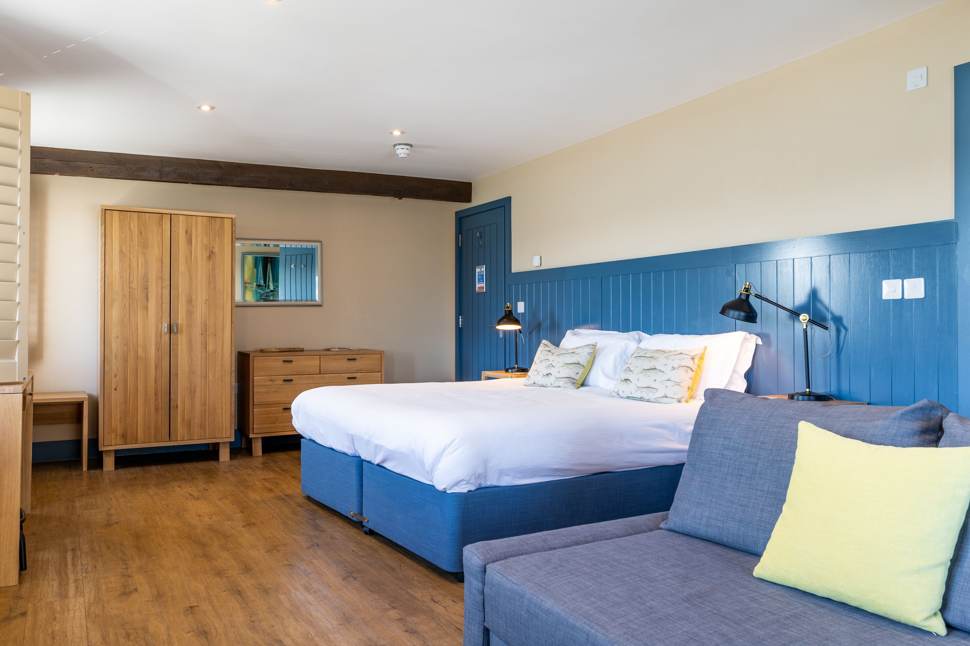 A bedroom with a bed, a wardrobe, a dresser, a bedside table, and a lamp.