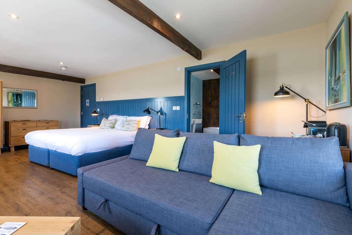 A bedroom with a large bed, a sofa, a desk, and a chair.