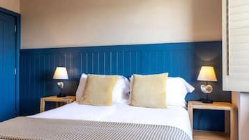 A hotel room with a bed, two bedside tables, and lamps.