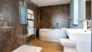 A modern bathroom with a glass-enclosed shower, a freestanding bathtub, and a white sink. - Seagate (Bideford)