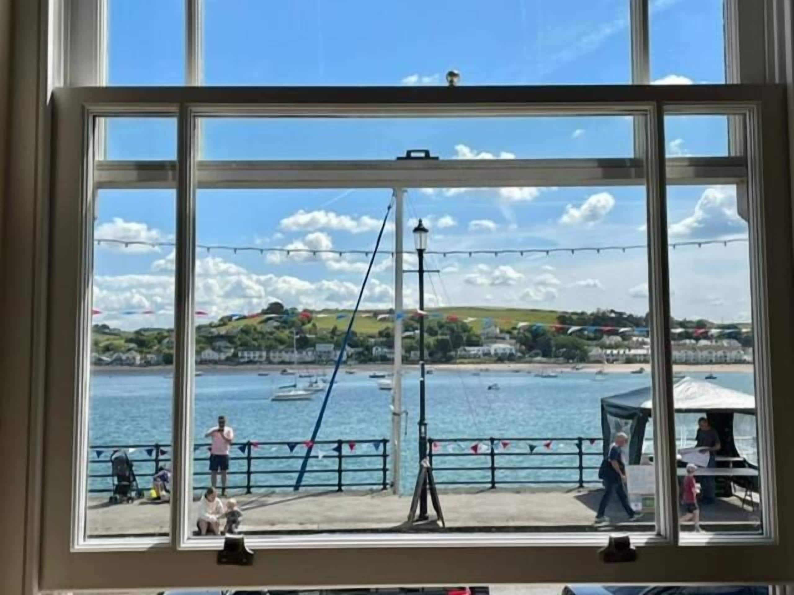 Una ventana con vista a una zona costera, incluyendo un muelle y una masa de agua.