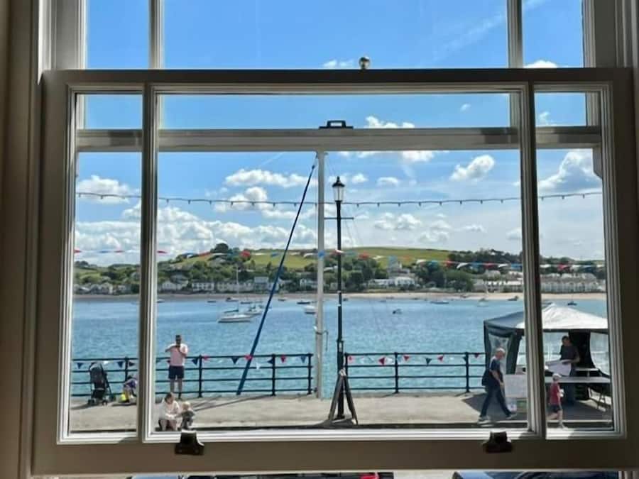 A window with a view of a waterfront area, including a pier and a body of water.