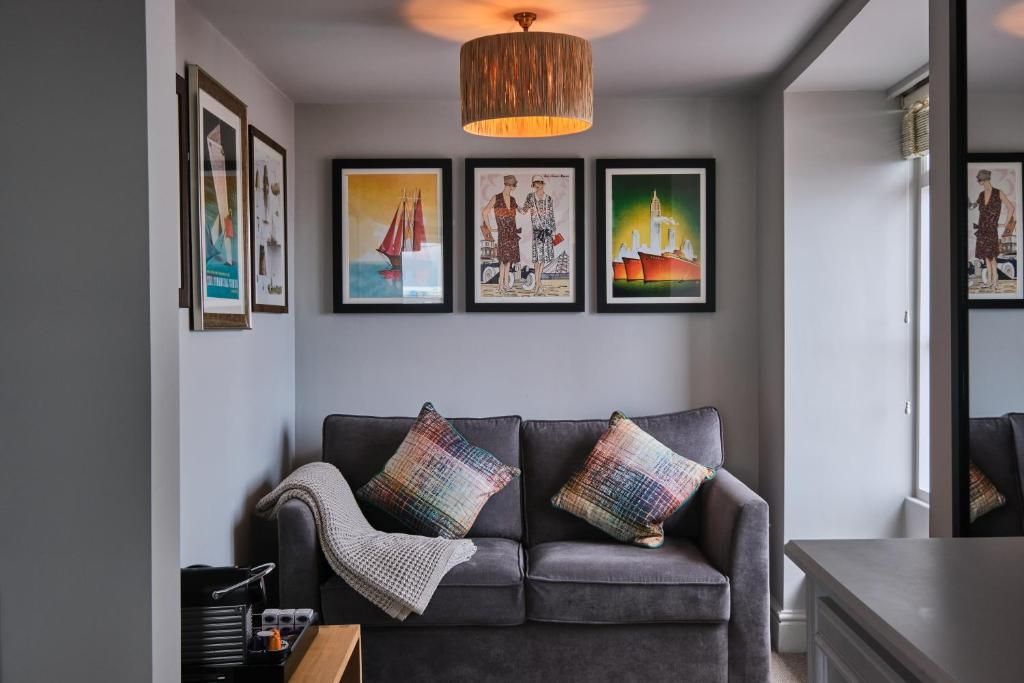 A modern living room with a grey sofa, colorful cushions, and framed artwork on the wall.
