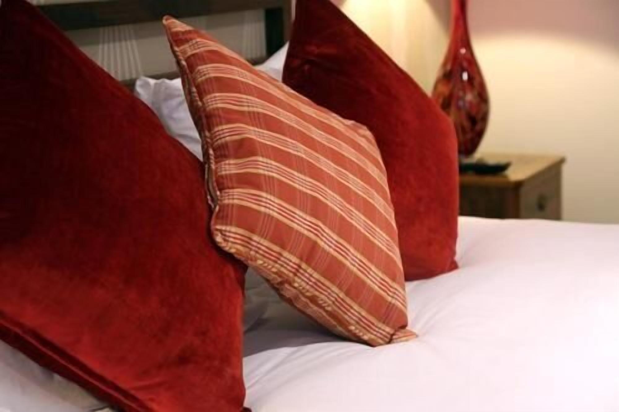 Una cama con almohadas rojas y una de rayas.