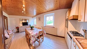Une cuisine chaleureuse avec un coin repas, un plafond en bois et une fenêtre laissant entrer la lumière naturelle.