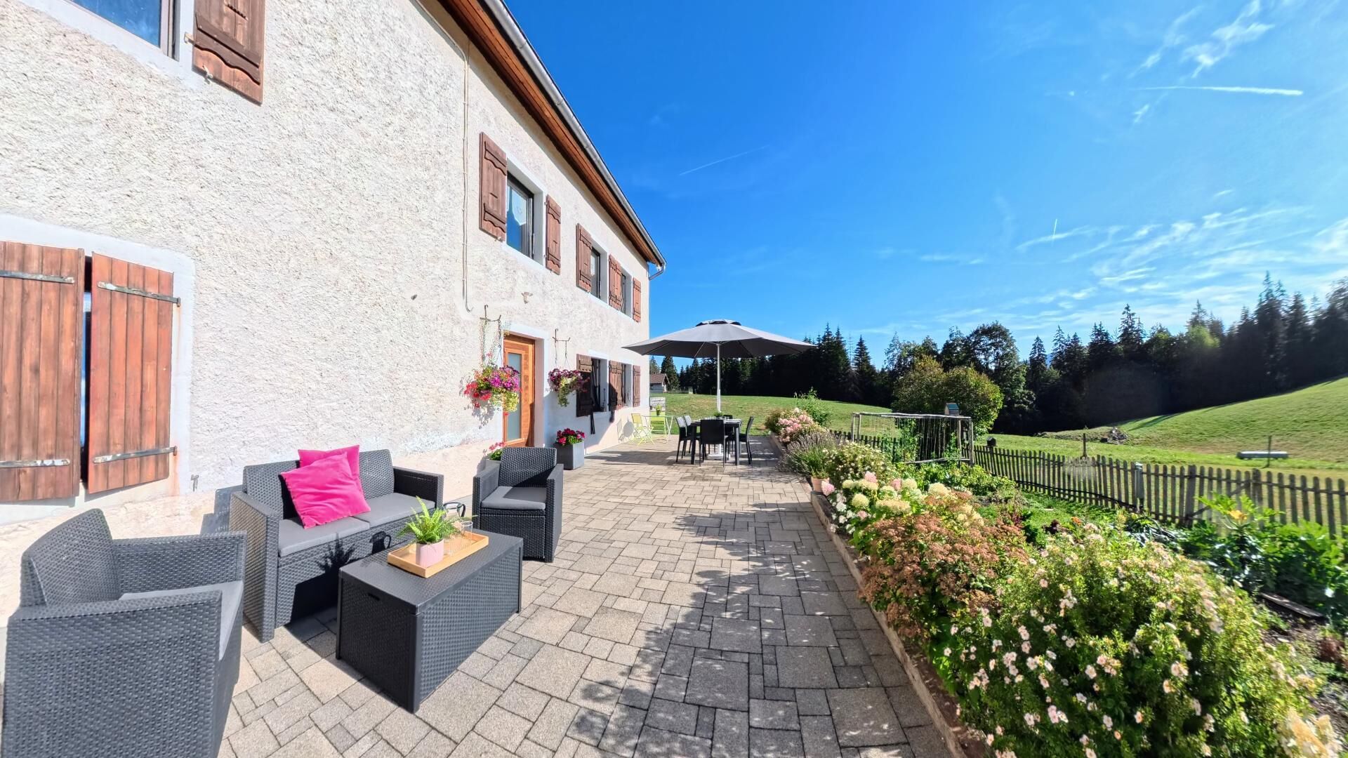 Un edificio con un patio arredato con mobili da esterno e una cesta di fiori appesa.