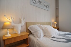 Une chambre à coucher comprenant un lit, deux tables de chevet, une lampe fixée au mur et un élément décoratif mural.