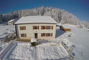 Un bâtiment à deux étages, dont le toit est recouvert de neige, avec une petite construction attenante.