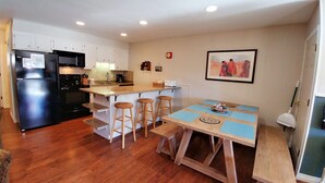 Une cuisine compacte équipée d’un réfrigérateur, d’une cuisinière et d’un four à micro-ondes. Elle comprend également un coin repas avec une table et des tabourets.