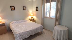 A bedroom with a bed, bedside lamps, a round table, and a window with curtains.