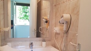 A bathroom with a white vanity, a mirror, a hairdryer, and a towel.