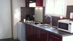 A compact kitchen with dark tiles, a built-in microwave, and a compact refrigerator.