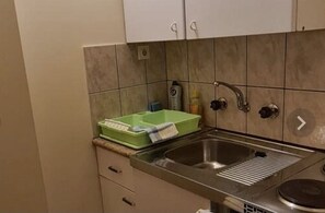 Een koelkast, een kookplaat, kookgerei, borden en bestek