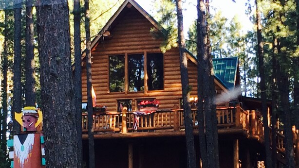 A wooden cabin with a balcony, surrounded by trees.