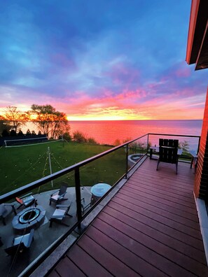 A deck with outdoor furniture, a view of the ocean, and a sunset. - The Retreat on Lake Michigan Spectacular 6 bd/4bth 4000 sqft (Kenosha)
