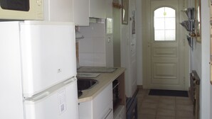 Una cocina con armarios blancos, un microondas, un refrigerador, un fregadero y una puerta con un reloj.
