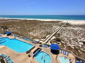 A resort with a large pool, a beach, and a boardwalk.