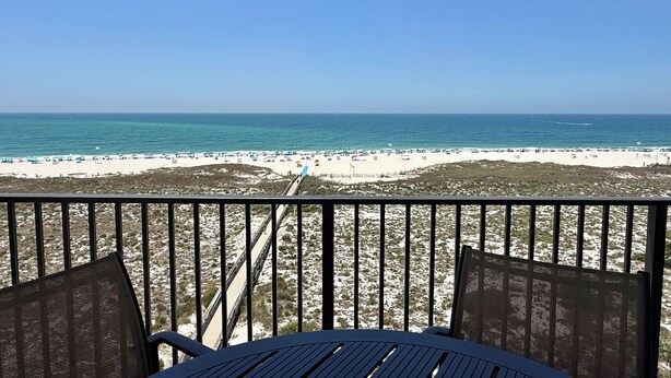 A beach view from a balcony with a table and chairs, a sandy beach, and the ocean. - Phoenix VI #606 - Resort Style complex owner's Beach Chairs Included in Rental (Orange Beach)