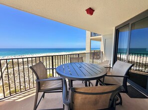 Un balcón con una mesa y sillas, vista a la playa, y una lámpara de techo roja.