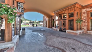 A hotel entrance with a stone facade, wooden doors, and a paved walkway leading to the lobby. - Sundial 1 BR in Canyons Village, private patio, outdoor pool and hot tubs, walk to hiking and biking (Park City)