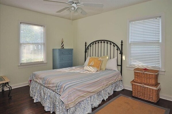 A bedroom with a bed, dresser, and two wicker baskets.
