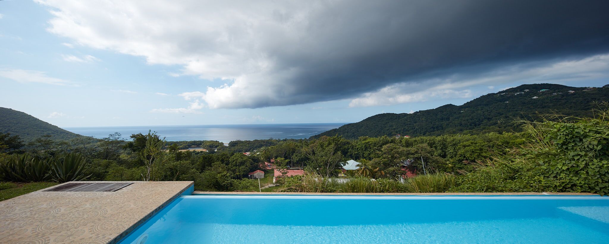 En swimmingpool med utsikt över ett kustlandskap och berg.