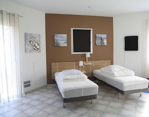 Quarto de hotel com duas camas, uma janela grande e obras de arte nas paredes.