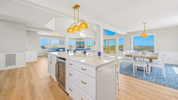A spacious kitchen with a central island, white cabinetry, and gold handles.