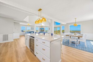 A spacious kitchen with a central island, white cabinetry, and gold handles. - Oceanfront Home in Waves with Private Pool, Hot Tub, and Home Theater (Waves)