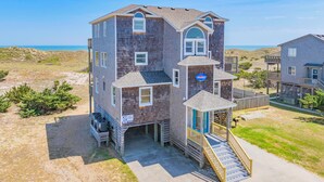A multi-story building with a beach view, a small porch, and a staircase leading to the entrance.