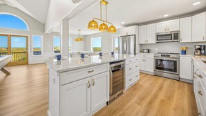 A modern kitchen with white cabinetry, stainless steel appliances, and a large island.