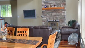 A spacious living area with a stone fireplace, a dining table with chairs, a sofa, and a fan. - Deruyter lake waterfront  (Deruyter)