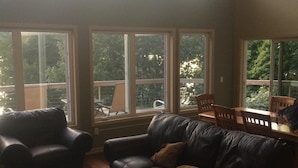 A living room with a leather sofa, a coffee table, and a dining table with chairs. There are large windows providing natural light. - Deruyter lake waterfront  (Deruyter)