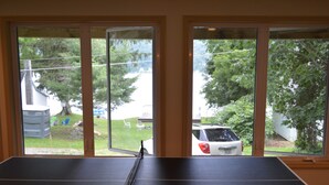 A ping pong table in a room with large windows overlooking a backyard. - Deruyter lake waterfront  (Deruyter)