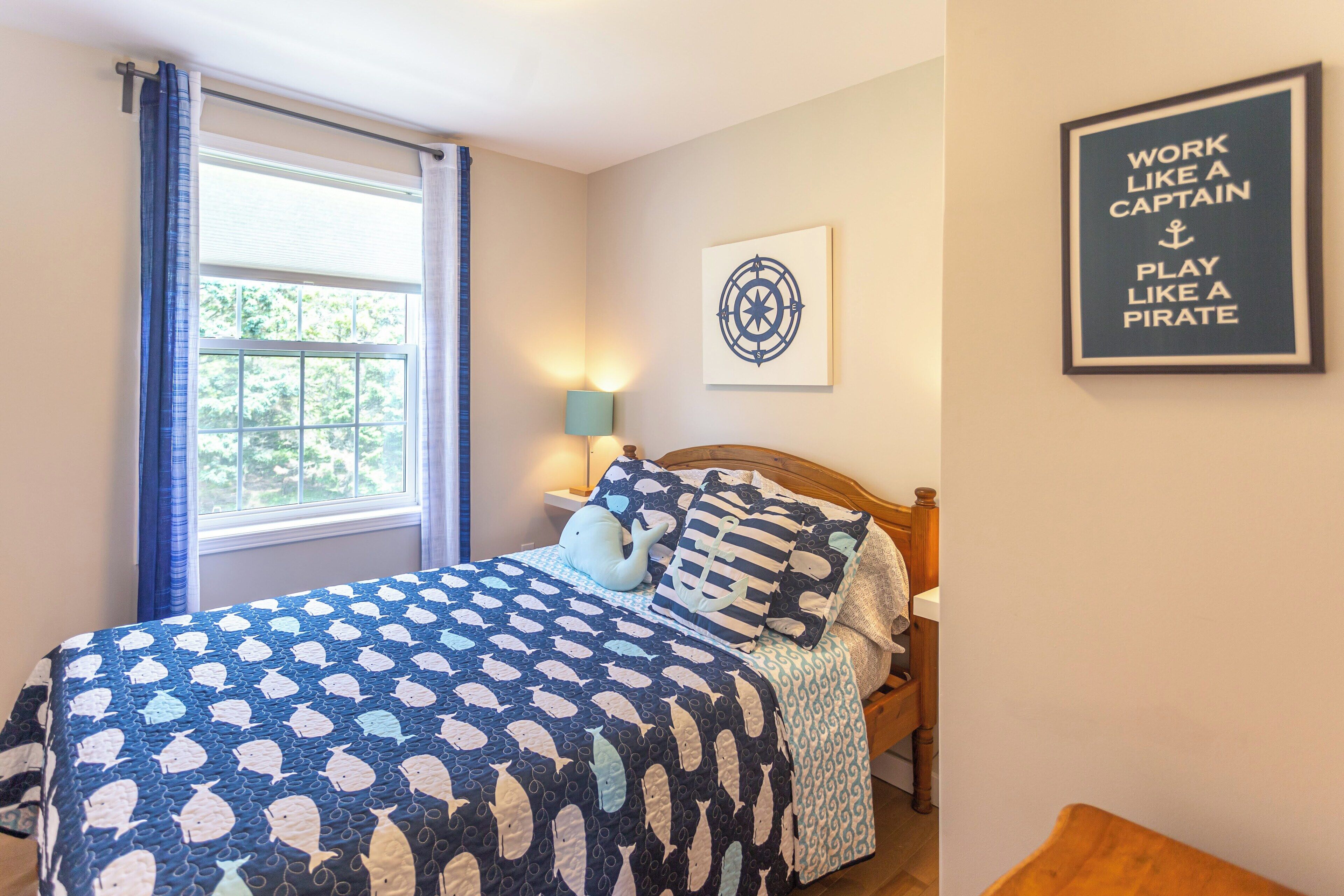A bedroom with a bed, a window with curtains, a wall-mounted lamp, and a motivational poster.