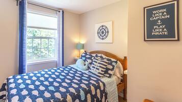 A bedroom with a bed, a window with curtains, a wall-mounted lamp, and a motivational poster.