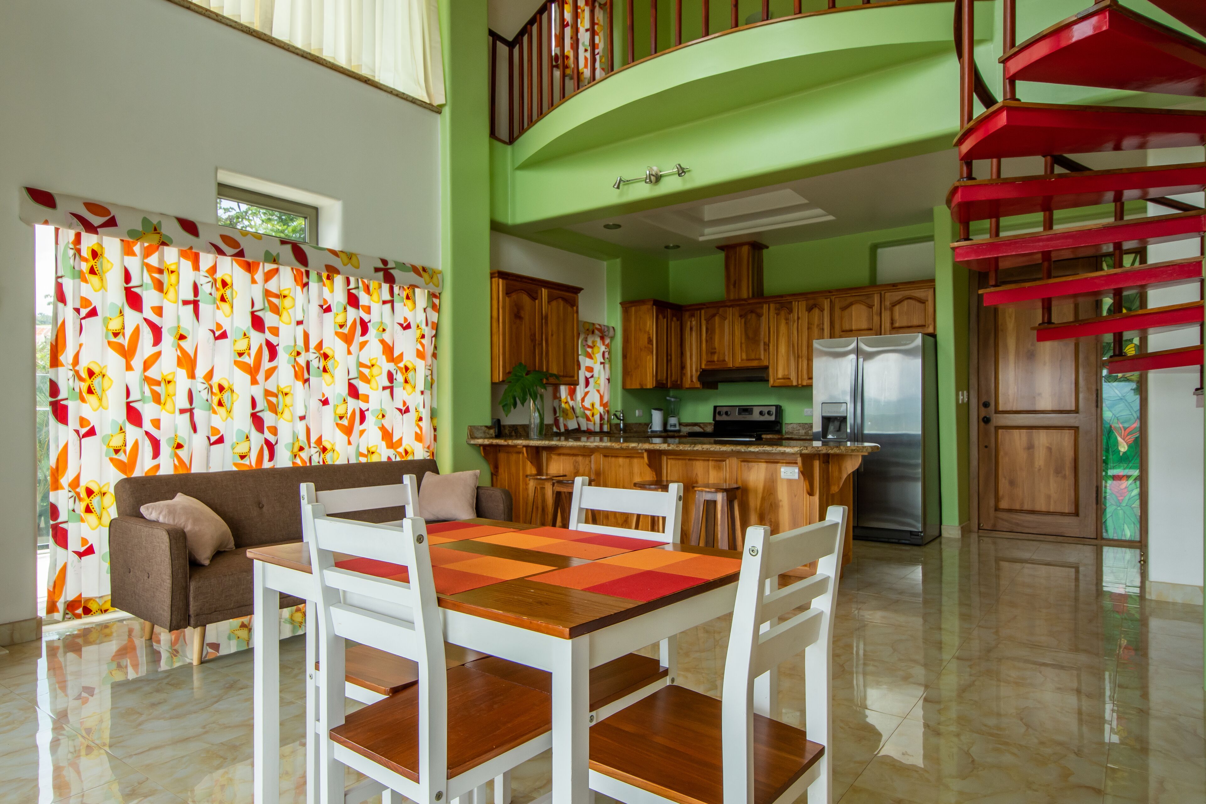 A spacious kitchen with wooden cabinets, a central island, and a red spiral staircase.