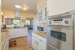 A modern kitchen with white cabinets, a stainless steel refrigerator, a microwave, and a vintage radio.