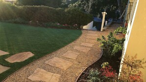A garden pathway with stepping stones and gravel, bordered by a hedge and various plants. - Views, Ocean/Mountain, Hot Tub, AC, Walk to Mesa Village, Gated Yard (Santa Barbara)