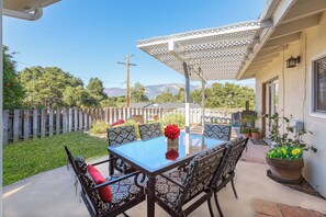 A patio with a table and chairs, a pergola, and a view of a mountain range. - Views, Ocean/Mountain, Hot Tub, AC, Walk to Mesa Village, Gated Yard (Santa Barbara)