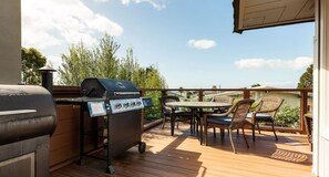 A deck with a grill, outdoor table, and chairs. - Remodeled Beach House w/Roof Top & Deck Ocean View (Aptos)