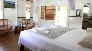 Un dormitorio con cama, una silla, una mesita y un cuadro en la pared.
