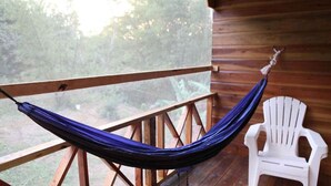Una hamaca sobre una terraza de madera con una silla de plástico blanca.